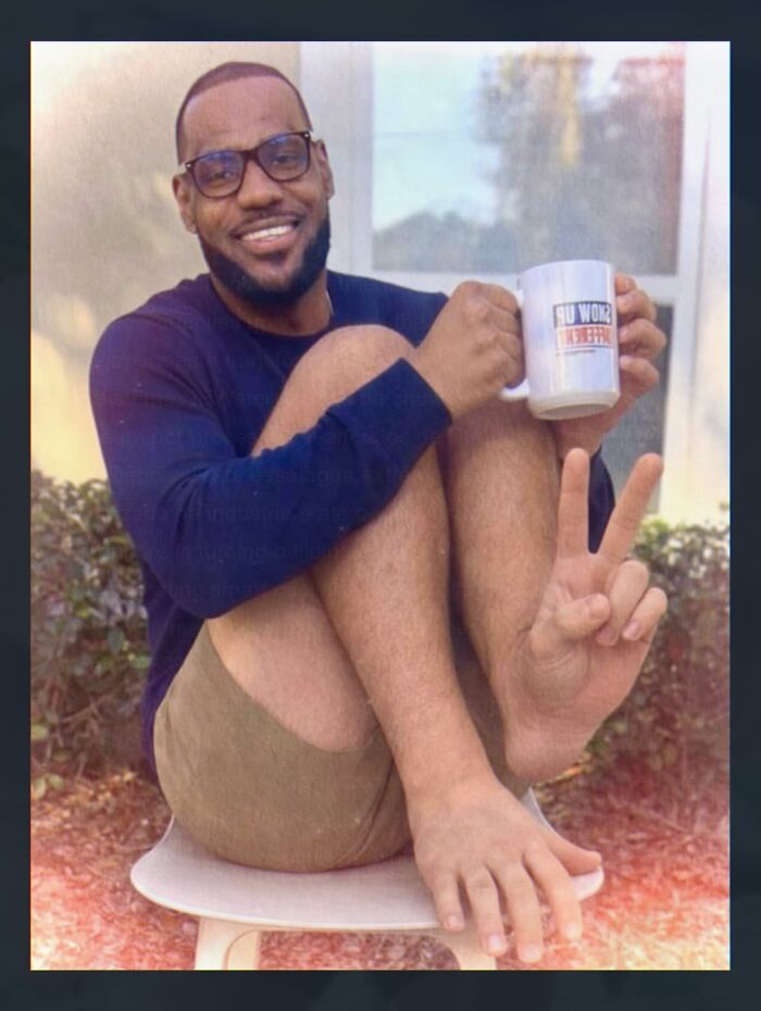 Smiling man sitting with legs crossed holding a mug and making peace sign