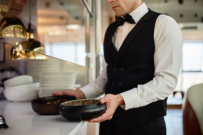 Waiter in vest holding bowls representing smooth criminals