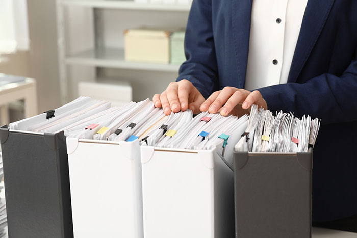 Person organizing legal files in binders on office desk