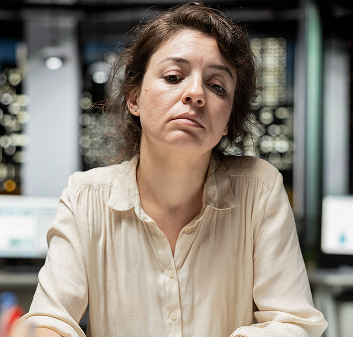Pensive woman in office with computer screens embodying smooth criminals idea