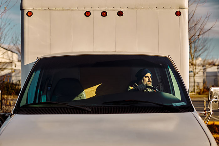 Delivery driver in truck embodying smooth criminals lifestyle