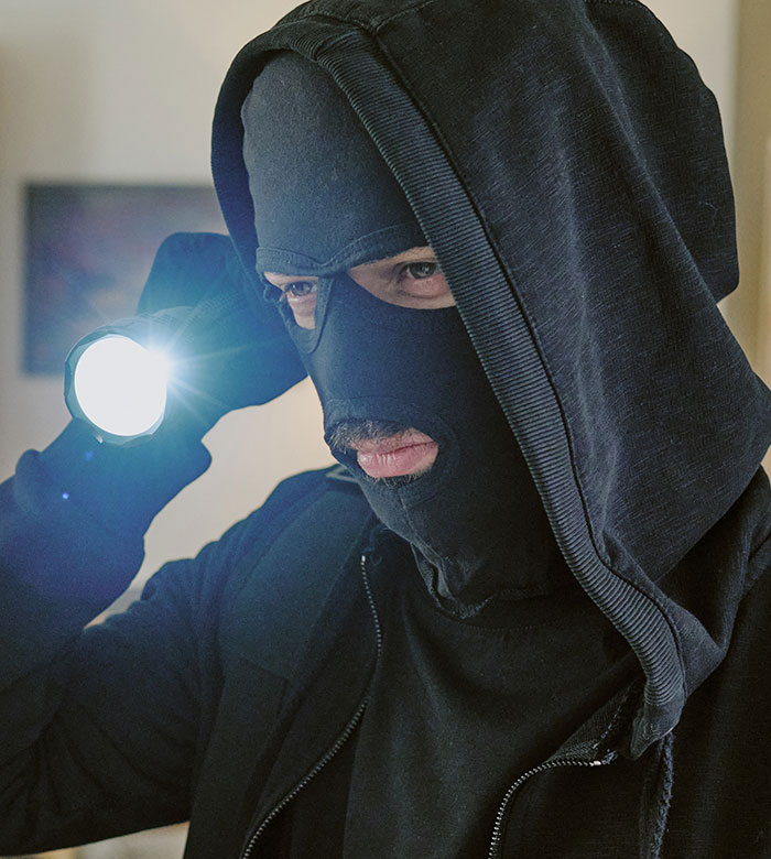 Hooded man with mask and flashlight illustrating smooth criminals