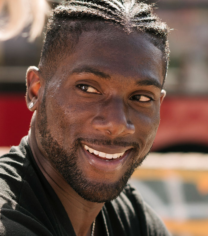 Smiling man with braided hair outdoors in casual setting