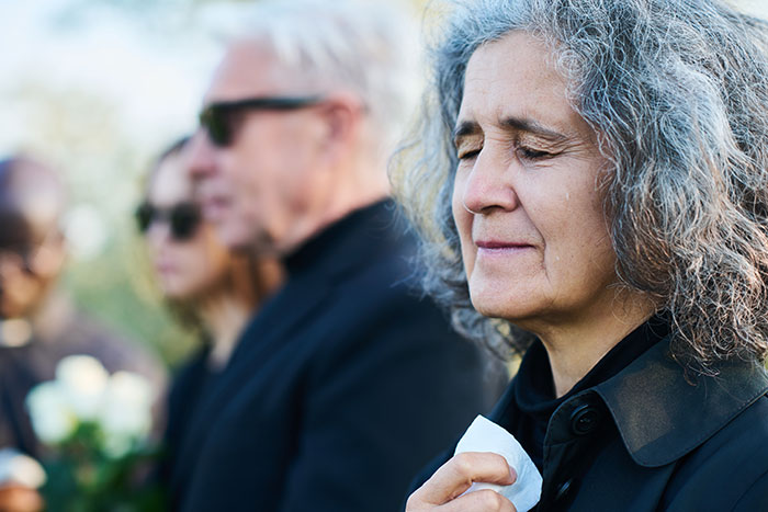 Woman crying with tissue at outdoor memorial service