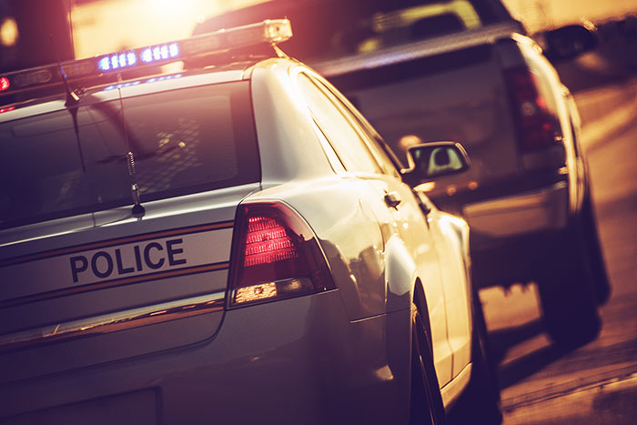 Police car with flashing lights during sunset traffic stop