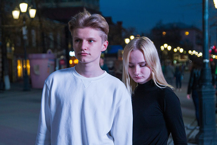 A 17-year-old teen, a blonde male, walks with a sad blonde female, showing the conflict from the dad's girlfriend.