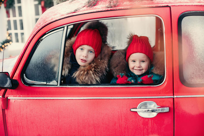 Two kids in red hats sitting in red car window Two kids in red hats sitting in red car window