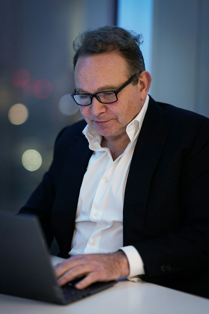Middle-aged man in suit and glasses working on laptop indoors