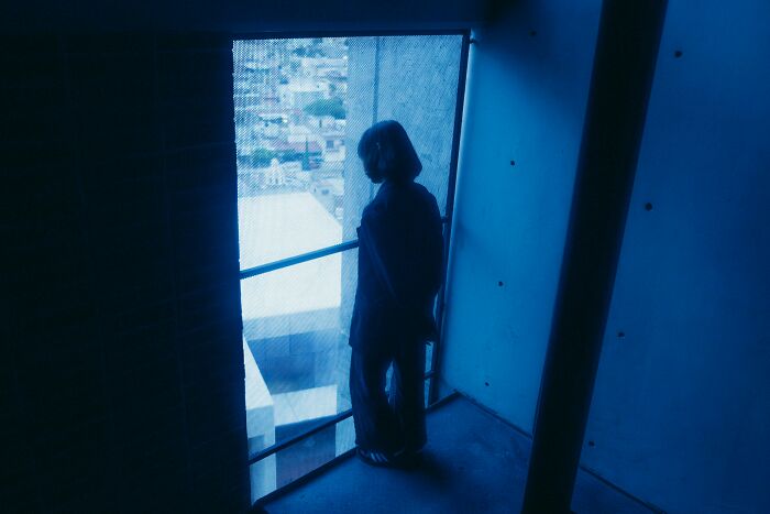 Shadowy person standing in dim hospital hallway near window