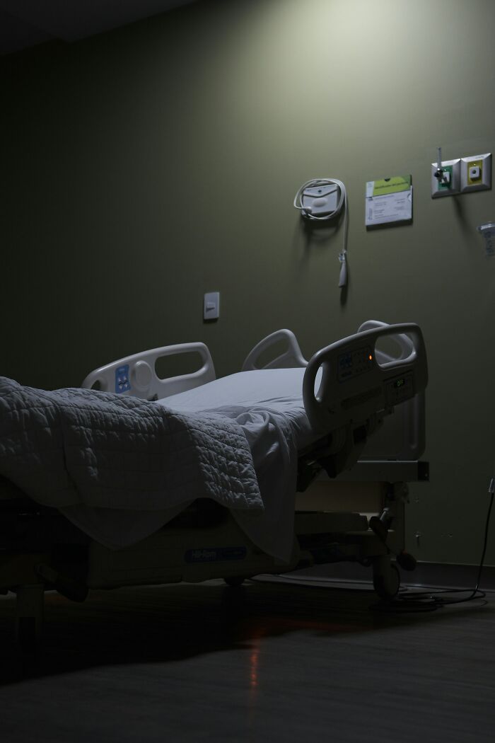Empty hospital bed in dimly lit room at night for creepy hospital stories