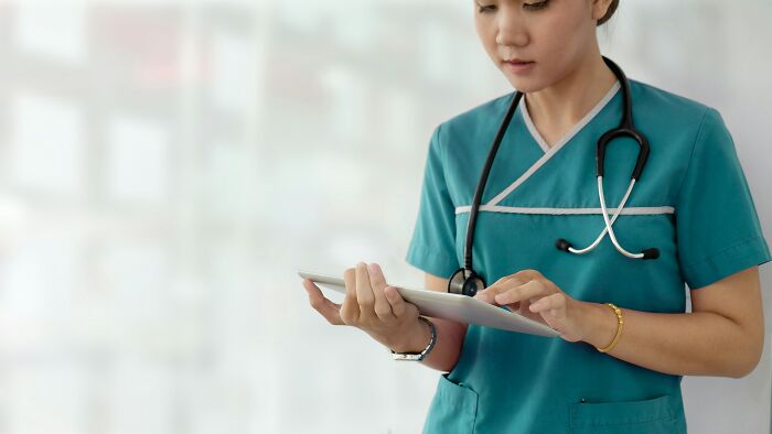 Medical worker in scrubs using digital tablet in hospital setting