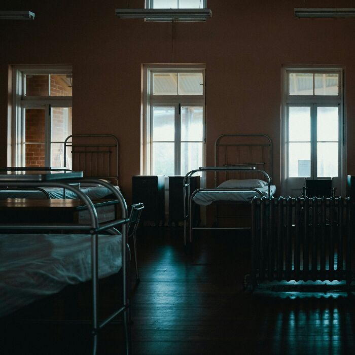 Empty hospital ward with metal beds and dim lighting