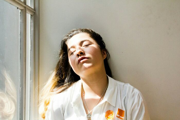Woman relaxing with eyes closed by window sunlight