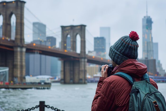 A person photographing the Brooklyn Bridge, depicting experiences while visiting the US.