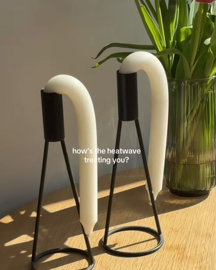 Two white candles bent over in their holders, indicating how Europeans are trying to survive the heatwave.