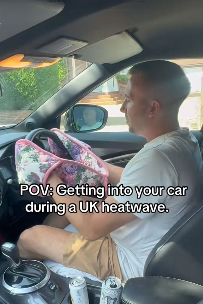 A man holding slippers to avoid burning his hands on the steering wheel during a heatwave.