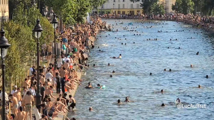Europeans gathered by and swimming in a river, trying to survive the heatwave.
