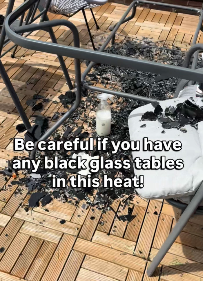 A shattered black glass table on a wooden deck due to the intense European heatwave.