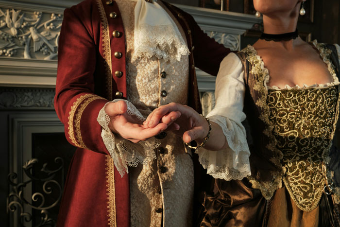 Hands of a couple dressed in vintage royal period costumes