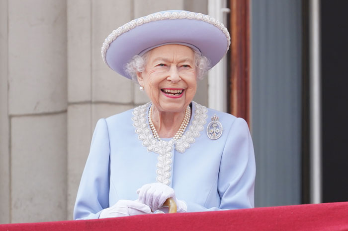 Smiling elderly queen in light blue outfit symbolizing royal surnames