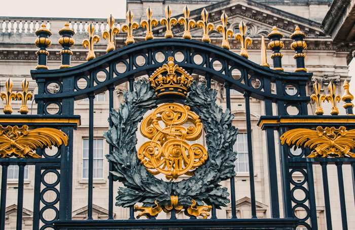 Ornate black gate with golden royal crest emblem at royal residence