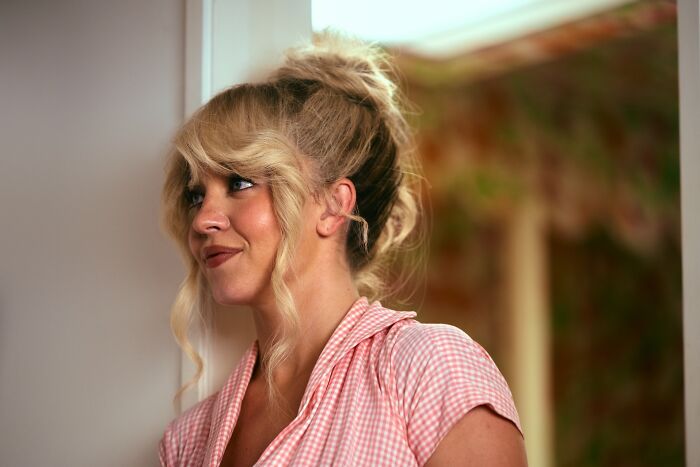 Woman smiling in pink gingham top with blonde hair styled in curls Woman smiling in pink gingham top with blonde hair styled in curls