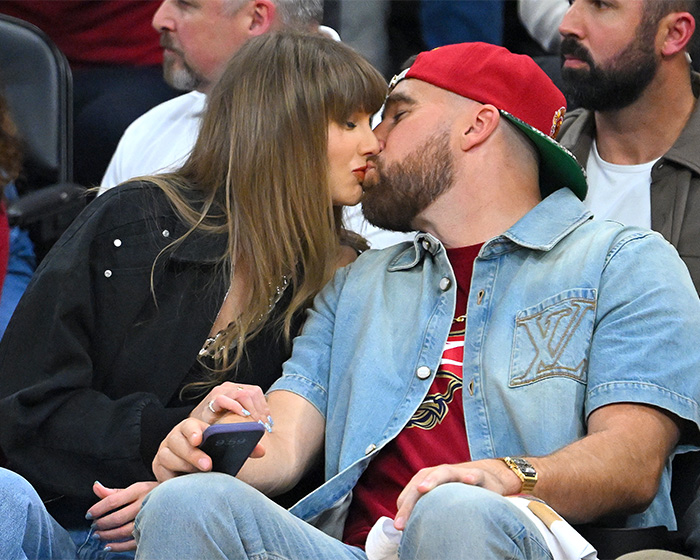 Taylor Swift and Travis Kelce share a kiss while seated, causing wedding backlash over alleged elitist plan.