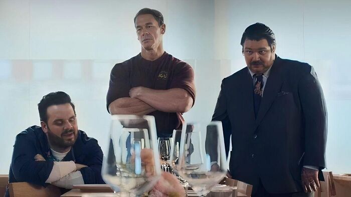 John Cena and other Berzatto family members from The Bear gather around a table with wine glasses.