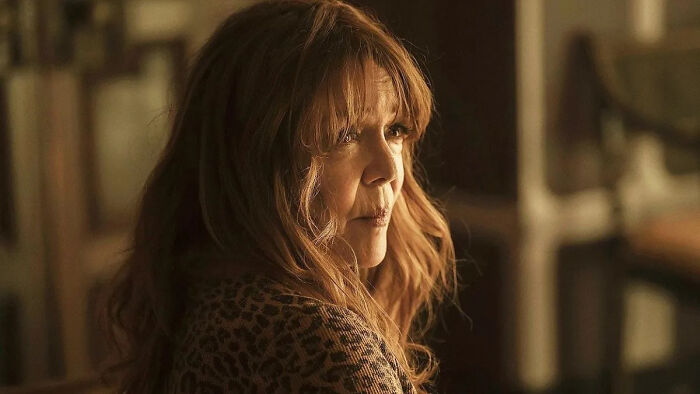 A pensive guest star Jamie Lee Curtis with long reddish-brown hair, looking over her shoulder in The Bear Season 5.