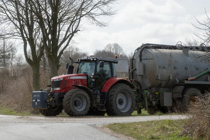 Tractor with large tank on rural road illustrating AI-caused great depression effects on farming