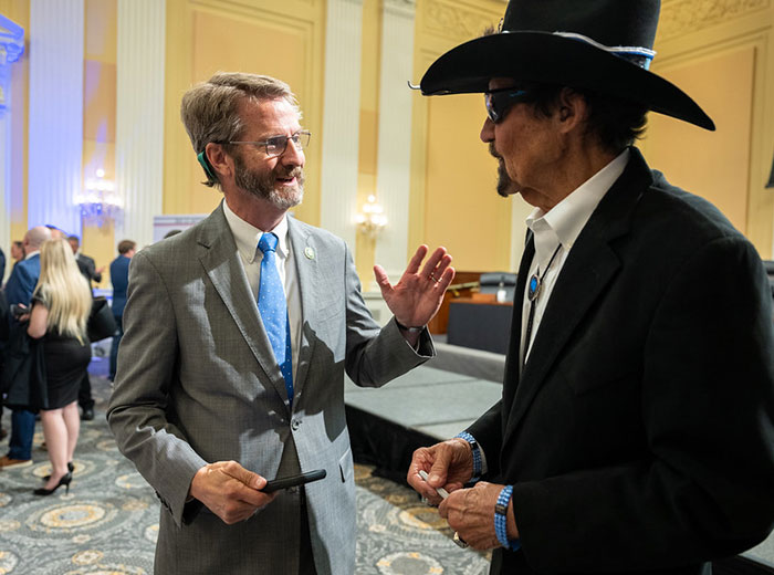 Two men talking at event with one wearing cowboy hat at Freedom 250 concert