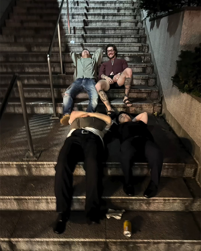 Four tourists lying and sitting on concrete steps at night, revealing a different side of Japan.