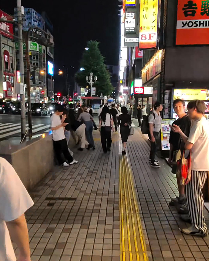 Night view of a bustling street in Japan, showing the dark side of urban life with many people.