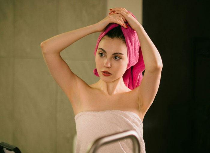 A woman with a pink hair towel on her head, looking surprised. Kid steals woman's hair towel. A woman with a pink hair towel on her head, looking surprised. Kid steals woman's hair towel.