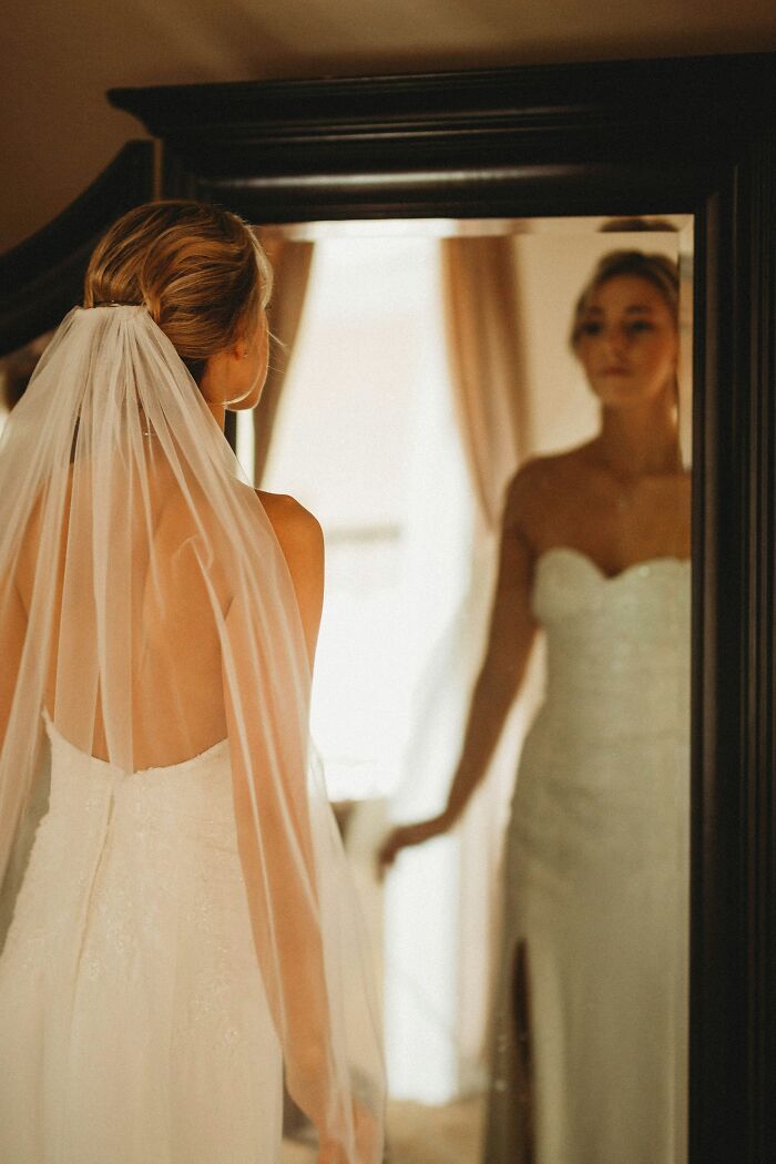 Bride in wedding dress looking at herself in mirror