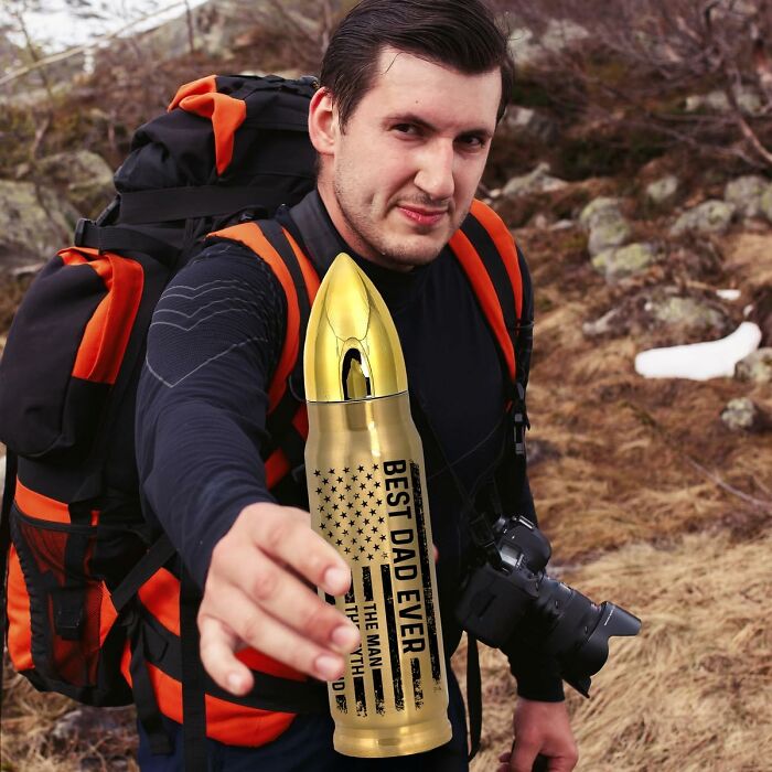 Man outdoors holding gold bullet-shaped best dad ever flask gift