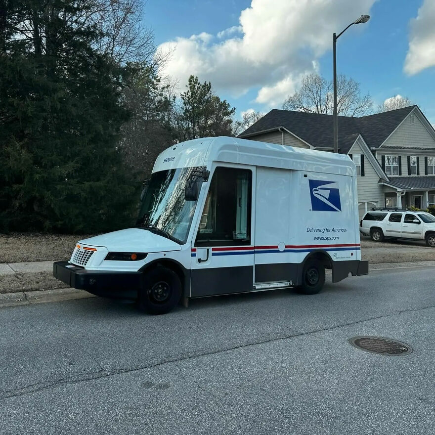 A white USPS mail truck, an ugly car that became legendary, parked on a suburban street.