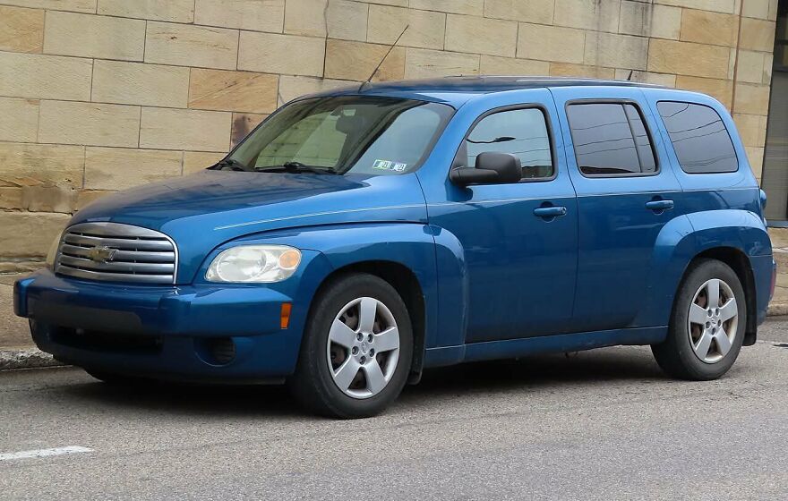 A blue Chevrolet HHR, one of the legendary ugly cars, parked by a brick wall.