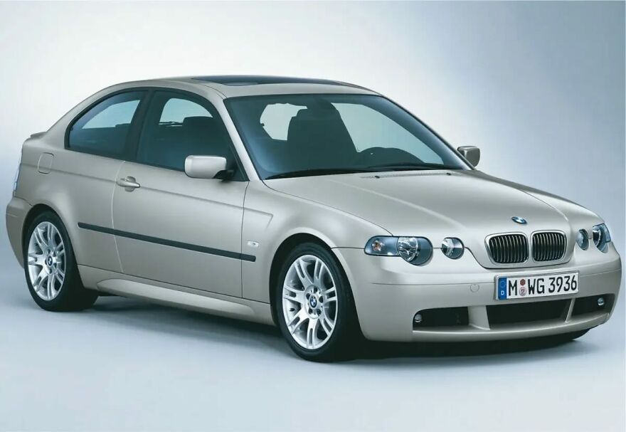 A beige BMW 3 Series Compact, an ugly legendary car, with a sunroof on a light background.