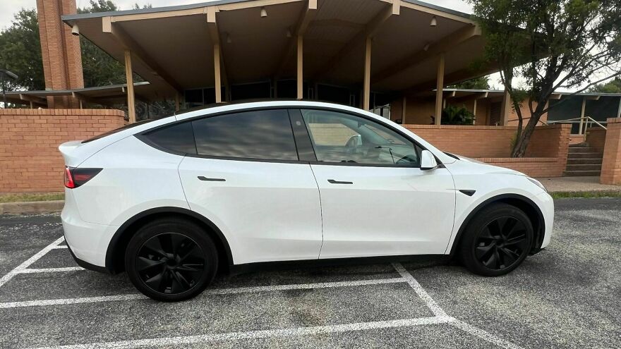 White Tesla Model Y, an ugly car that became legendary, parked in a lot.