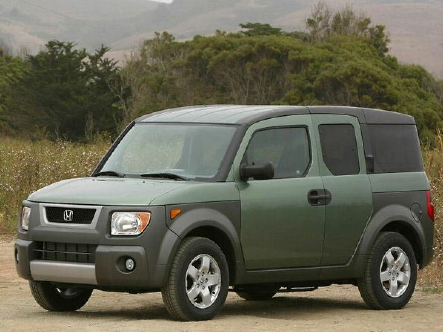 Green Honda Element, an ugly car that became legendary, parked on a dirt road.