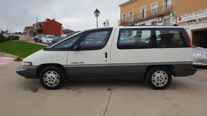 A white and grey Chevrolet Lumina APV minivan, an ugly car that became legendary, parked on a street.