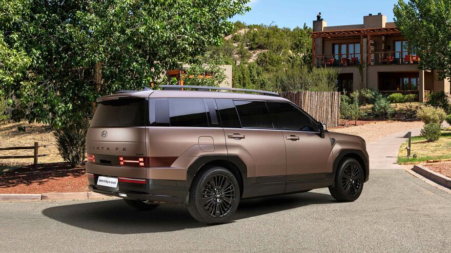 A brown, ugly car, possibly a Hyundai Santa Fe, parked on a paved driveway with a house in the background. Legendary design.