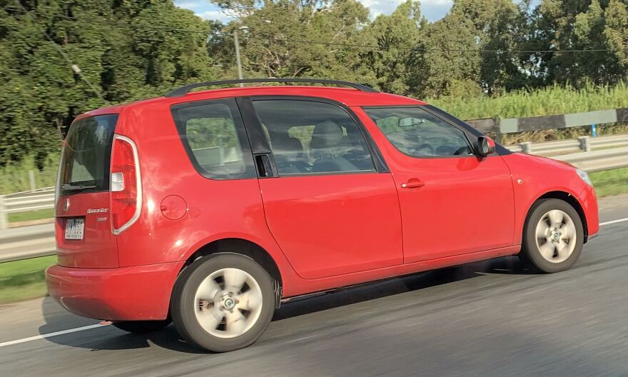 Red Skoda Roomster driving on a highway, a legendary ugly car with distinctive rear design