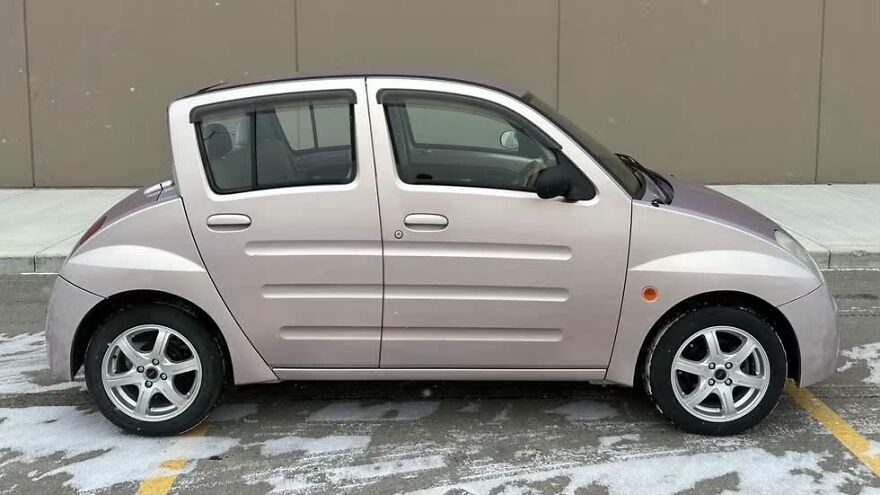 A light pink ugly car, a microcar style, on a snowy street, a legendary ugly car.