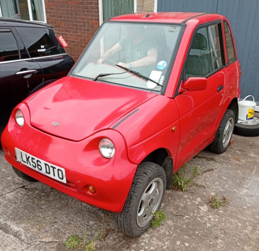 A small red microcar, an ugly car that became legendary, parked on a paved surface.