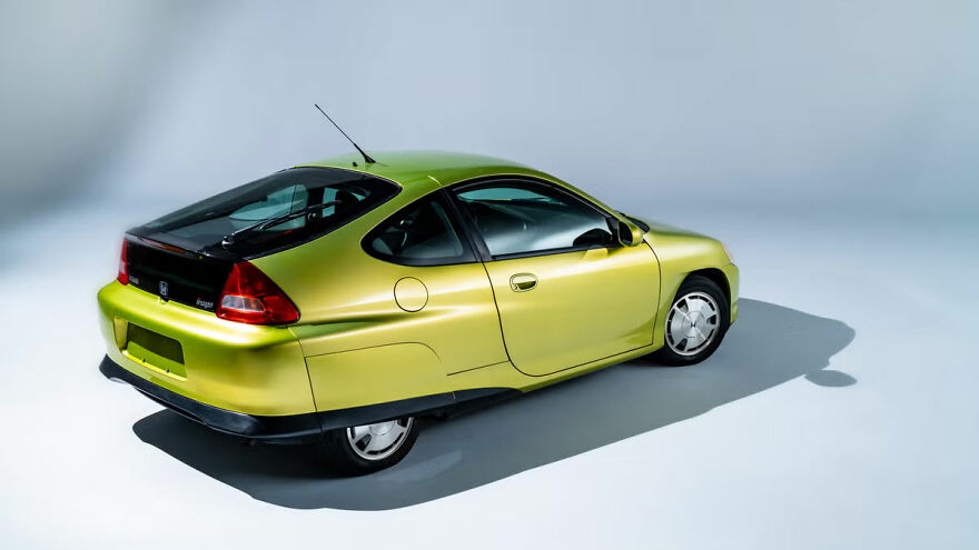 A lime green Honda Insight, one of the ugly cars that became legendary, viewed from the rear.