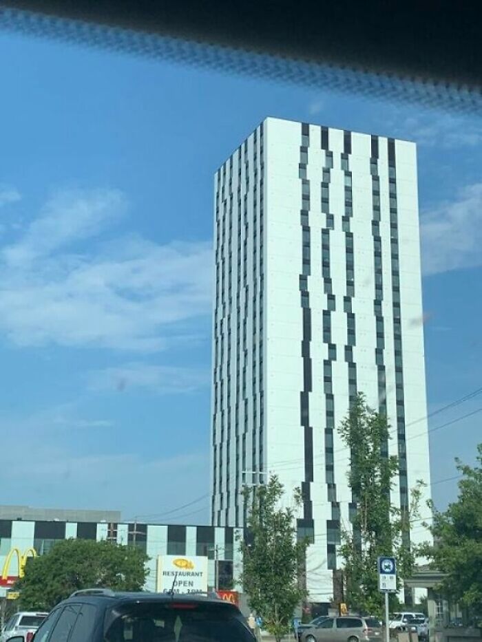 A tall, white skyscraper with irregularly placed dark windows, illustrating a questionable architecture and design fail.