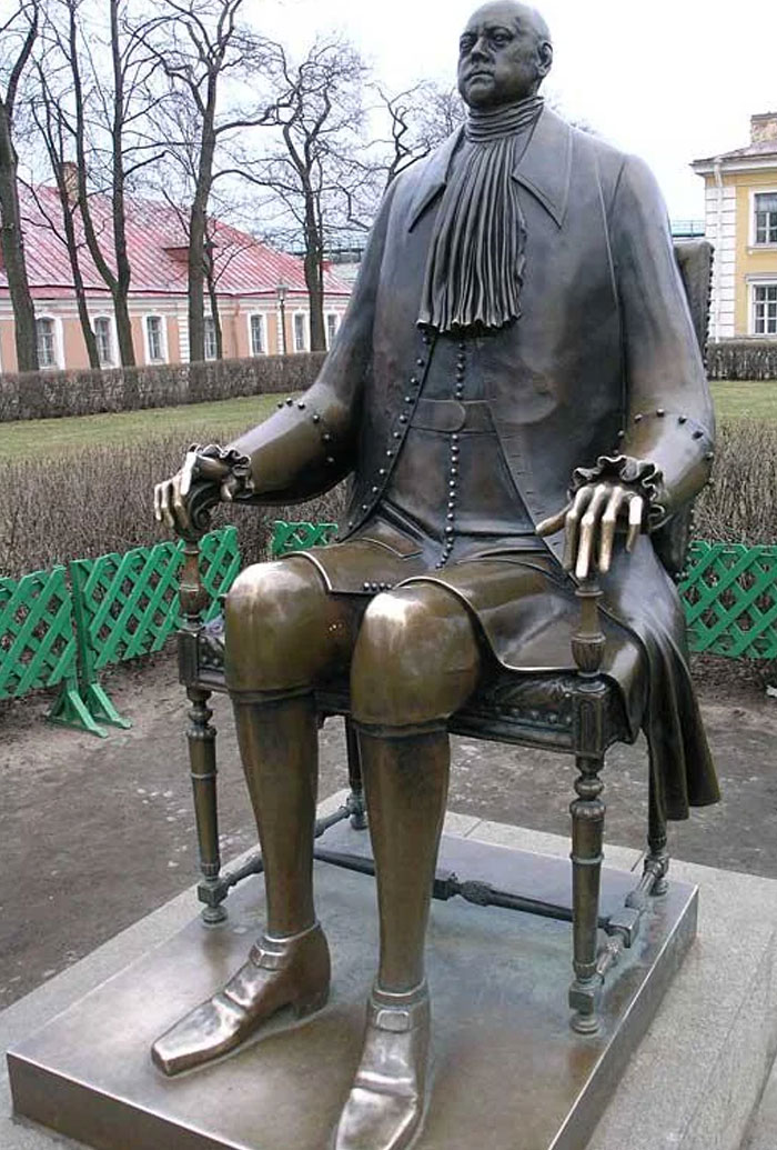 Unusual bronze statue of a seated man with long cuffs and exaggerated legs