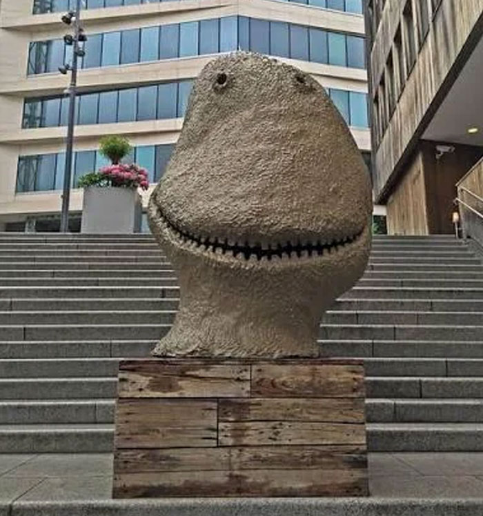 Ugly monument sculpture with a large smiling face on city stairs
